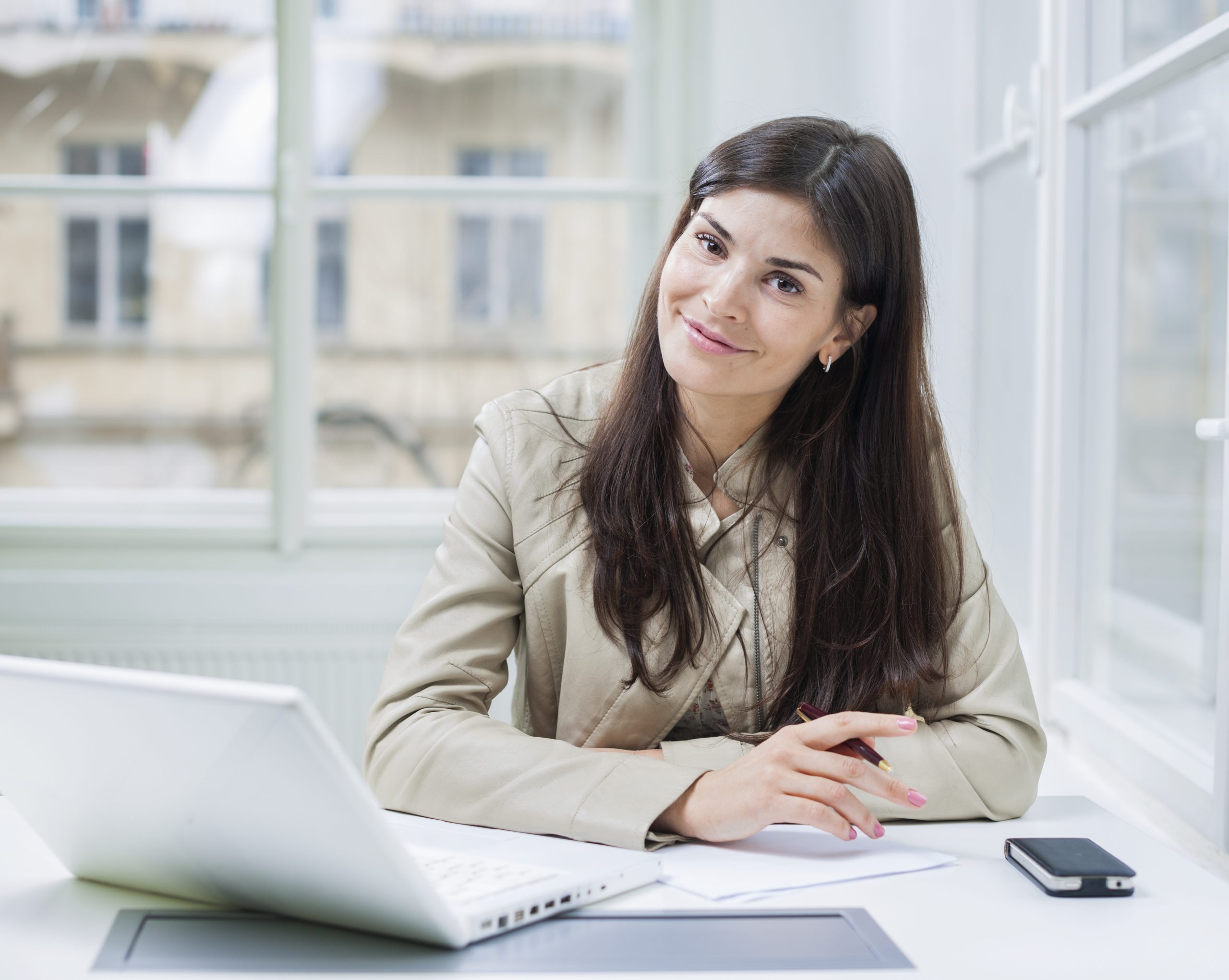 Portrait of confident businesswoman with laptop sitting at office desk